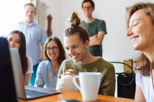 office-group-smiling-in-front-of-a-laptop